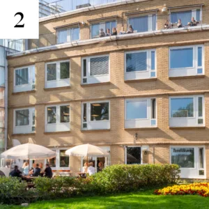 Byggnad i Alviks strand med människor på uteterrass och balkong.